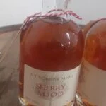 To flasker 'NY NORDISK MJØD SHERRY MJØD' på 35 cl med gyldenbrun væske og rød vokslignende forsegling, på en træoverflade.
