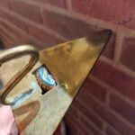 En hånd holder den murskeformede øloplukker, så en blå kapsel sidder i bladets åbning.