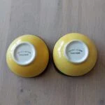 To vintage håndmalede tapasskåle med gule undersider og 'Del Rio Salado Hand Paint' mærkning på et træbord.