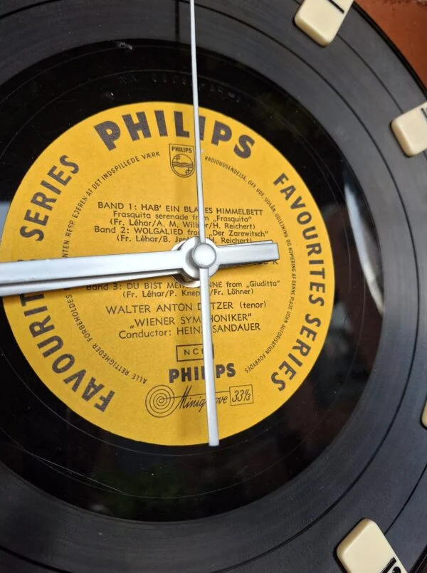 Et nærbillede af urskiven på et LP-ur, der viser Philips branding og tidsmarkeringer af dominobrikker.