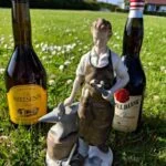 Beslagsmedsfiguren står i græsset mellem Dr. Nielsen’s Bitter og Gammel Dansk.