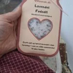 En hånd holder en pose 'Lavendel Fodsalt' fra Villasnak.dk, med en hjerteudskæring, der viser saltet.