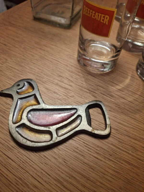 Et nærbillede af et gennemsigtigt Beefeater gin glas med et tydeligt rødt og gult logo, hvorpå der står 'Beefeater Made in London'.