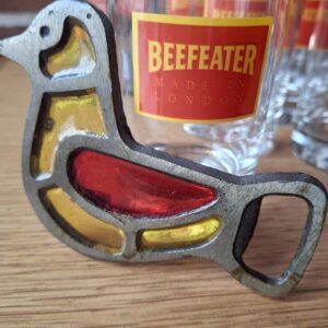 Nærbillede af en tom Beefeater London Dry Gin flaske, tydeligt visende etiketten med Beefeater-figuren og produktinformation. Beefeater glas i baggrunden.
