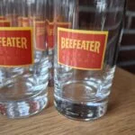 Nærfoto af klare Beefeater-glas med røde og gule logoer og kraftigere bunde.