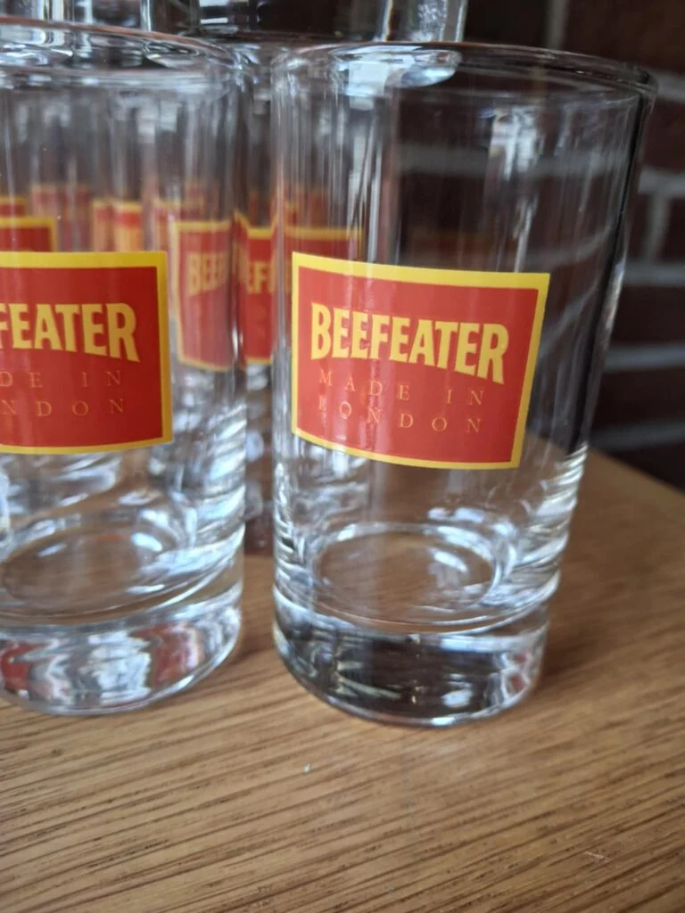 Nærbillede af et klart, lige Beefeater-glas med rødt og gult Made in London-logo.