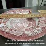 En 22 cm engelsk dyb tallerken i rød fajance med landskabsmotiv, et målebånd viser størrelsen.