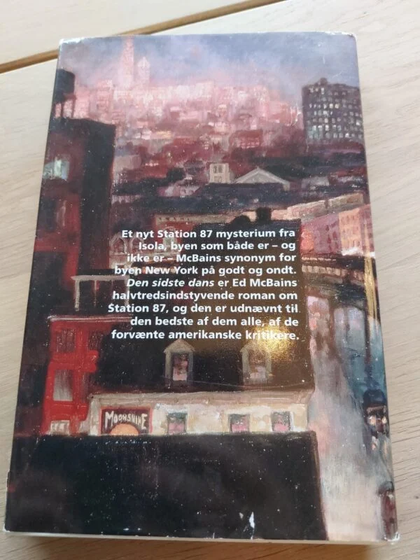 Bagsiden af 'Den sidste dans' af Ed McBain, med et billede af bygninger og bogbeskrivelse.