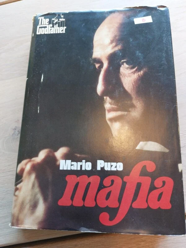 Forsiden af bogen 'Mafia' af Mario Puzo, med et portræt af en mand og rød titeltekst.