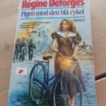 Forsiden af Pigen med den blå cykel af Régine Deforges med en kvinde ved en cykel og soldater i baggrunden.