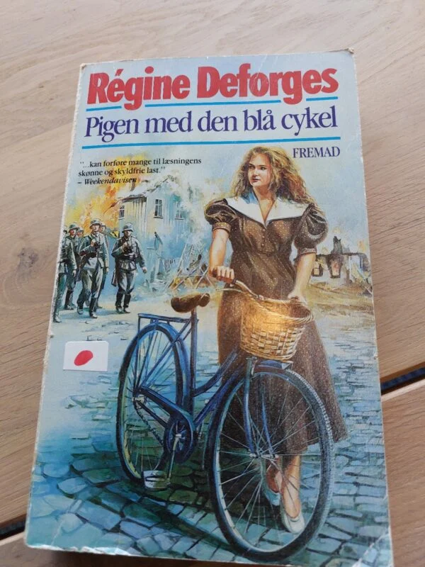 Forsiden af Pigen med den blå cykel af Régine Deforges med en kvinde ved en cykel og soldater i baggrunden.