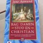 Blåt paperbackomslag med Jane Aamunds navn, rødt titelfelt, maleri fra hoffet og en lille hvid mærkat med rød markering.