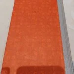 Bagsiden af den orange, mønstrede hardbackudgave af 'Drama i Cirkus' med grå bogryg.