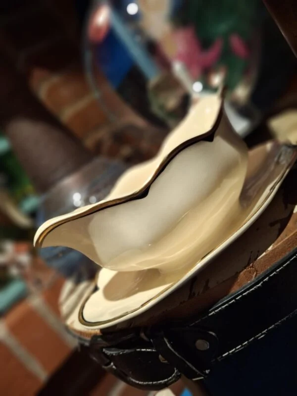 En hvid elegant sauceskål med guldkant, tilhørende et vintage stel, placeret på et træunderlag.