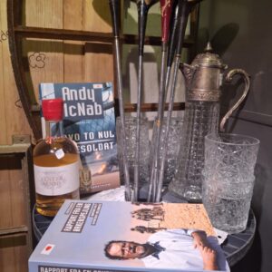 En elegant glaskande med reliefmønster og to matchende drikkeglas, en flaske og bøger.