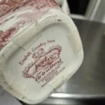Nærbillede af Grindley 'English Country Inns' stempel under en kande med rød transferprint.