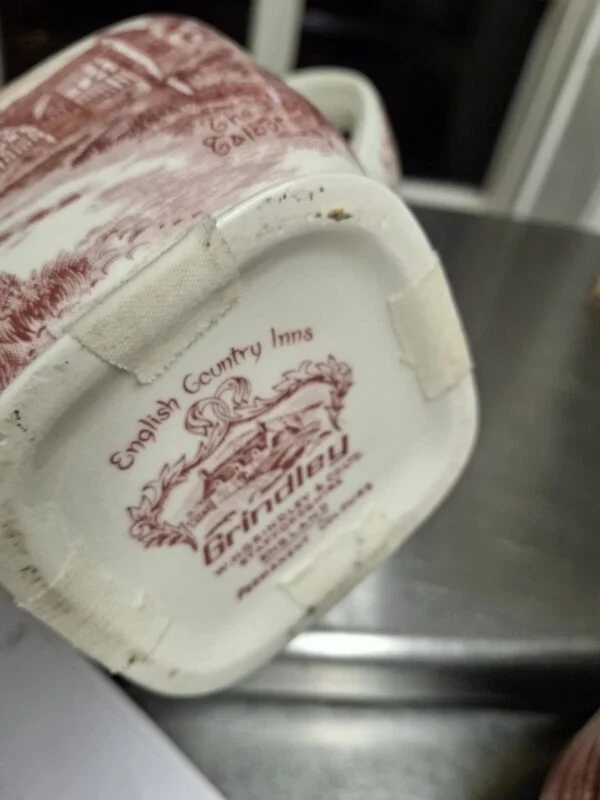 Nærbillede af Grindley 'English Country Inns' stempel under en kande med rød transferprint.