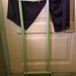 En høj, mintgrøn retro personvægt fra Lindells med en bog om psykologi liggende på foden, mod en hvid dør.