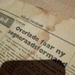 Nærbillede af avispapir fra Aalborg Amtstidende i bunden af den grønne kuffert.