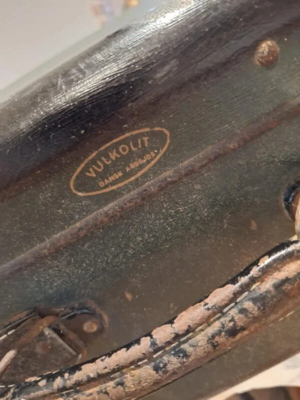 Nærbillede af mærkets logo 'Vulkolit - Dansk Arbejde' på en patineret mørkegrøn vintage rejsekuffert.