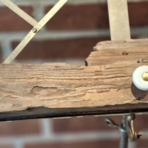 Sideskud af en unik knagerække af drivtømmer med synlig patina og to hvide porcelænsknopper, en med et prisskilt.