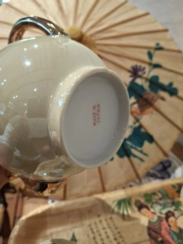 Undersiden af en kande med rød mærkning Made in Japan og en lys fodring.