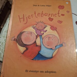 Forsiden af bogen 'Hjertebarnet' af Dan & Lotta Höjer, med illustration af en familie og et barn, der svæver opad, med teksten 'Et eventyr om adoption'.