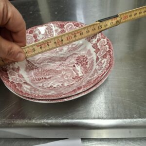 Hånd måler en engelsk fajance skål med rund kant, 15,5 cm, rød transferprint af herregårdslandskab.