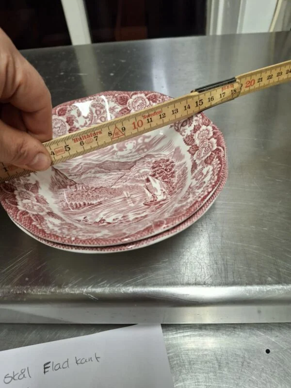 Hånd måler en engelsk fajance skål med rund kant, 15,5 cm, rød transferprint af herregårdslandskab.