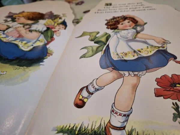 Opslag i Abelones elverkrone med en pige i blå nederdel og hvidt forklæde, blomster og dansk tekst.
