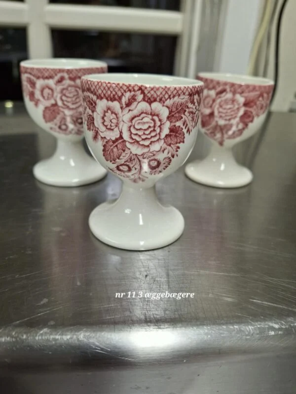 En engelsk lågkrukke i hvid fajance med rød transferprint, prydet med et blomstermotiv.