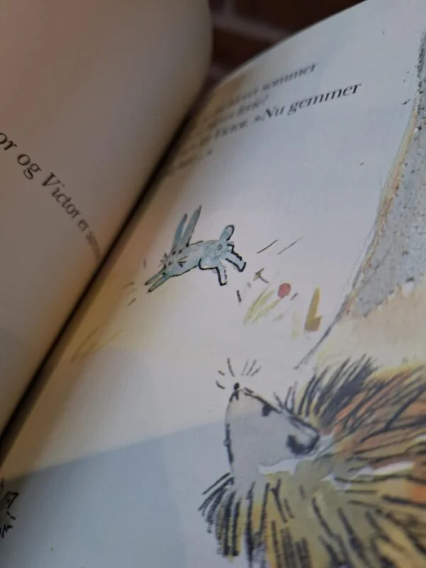 Åben børnebog 'Hector og Victor er gode venner' der viser en illustration af et pindsvin og en kanin, der hopper.