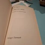 Indersiden af bogen 'I Herrens navn' af Jack Higgins, der viser titel, forfatter og forlag 'Forlaget Danmark'.