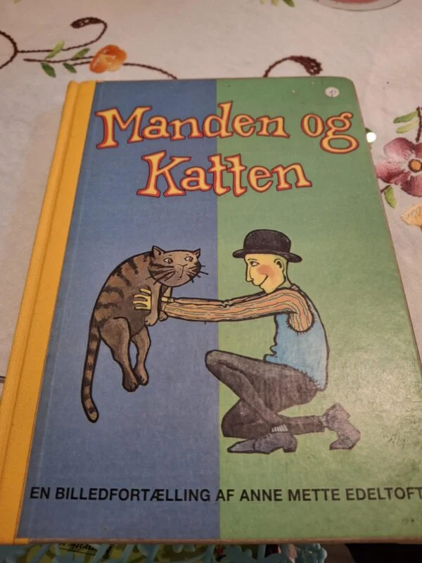 Forsiden af bogen 'Manden og Katten', en billedfortælling af Anne Mette Edeltoft, med illustration af en mand der holder en kat.