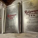 Tre blanke tedåser med Ridgways Five O’Clock Tea-tekst i rødt og sort, vist med låg.