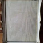 En stor, hvid fotoramme med guldkant og dekorative hjørner, stående bag to Holmegaard glasskåle (én frostet, én klar).