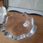 Nærbillede af en hjørnedetalje på en hvid vintage fotoramme med guldkant og ornamenteret metaludsmykning.