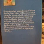 En stak på fem bøger i forskellige farver og størrelser med en blomsterdekoreret kaffekop og småkager på en lyserød hækledug.