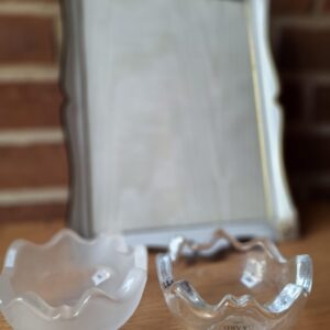 Nærbillede af en frostet Holmegaard glasskål med blødt buede kanter, placeret på et træbord. En fotoramme er uskarpt i baggrunden.