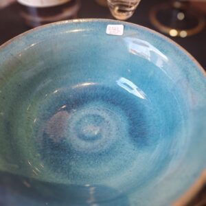 Nærbillede af indersiden af en hånddrejet, turkisblå keramikskål med et tydeligt spiralmønster i bunden.