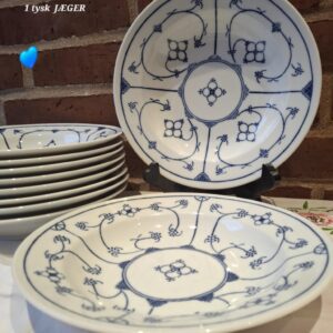 En stabel på ca. 9 hvide, dybe tallerkener fra Kahla med fattigmands muselmalet mønster i blå, set op mod en murstensvæg.