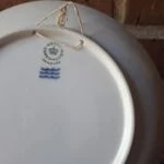 Bagsiden af en Royal Copenhagen-platte med Denmark-stempel, tre bølger og en ophængssnor.