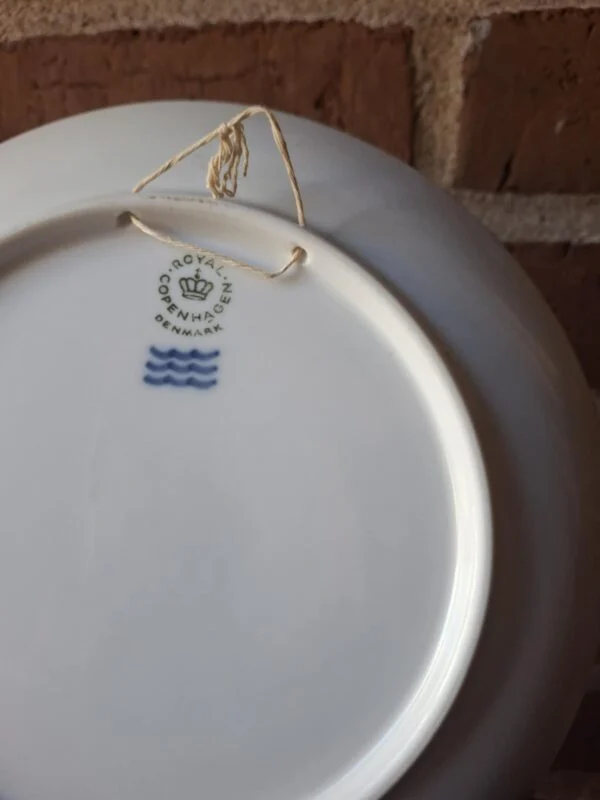 Bagsiden af en Royal Copenhagen-platte med Denmark-stempel, tre bølger og en ophængssnor.
