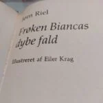 Nærbillede af bogryggen på 'Frøken Biancas dybe fald' af Jørn Riel, med grønt og beige design og gulddetaljer.