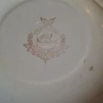 Undersiden af en tallerken med et brunligt Egersund Norway-stempel med skib og fugl.