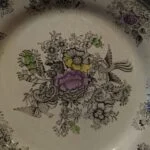 Nærbillede af fugle, sort blomstermønster og lilla, gule og grønne farvefelter på en Egersund-tallerken.