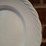 Nærbillede af kanten på en hvid Hanley Ware 'Satin White' flad tallerken, der fremhæver den flettede reliefdetalje.