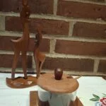 Vintage Lütjhøe Wood sennepskrukke i teaktræ og glas med matchende ske, samt to teaktræsrådyr på fælles fod. Placeret på hvid dug foran murstensvæg.