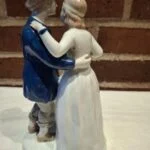 Bagsidebillede af en Schwarzburger porcelænsfigur af et dansende par. Manden i blå jakke, kvinden i hvid kjole, tæt sammen.