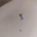 Billede af bunden af en porcelænsfigur, der viser mærket en krone med et 'S' og teksten 'GOR' nedenunder i blåt.